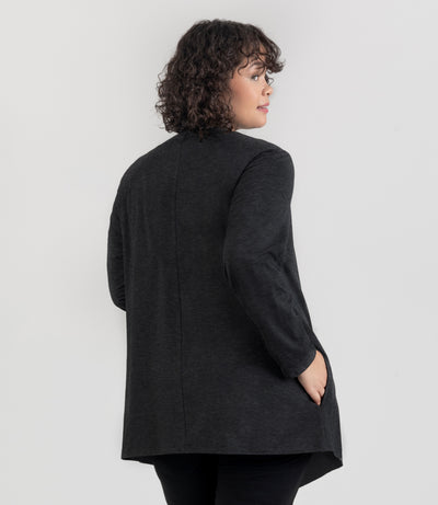 JunoActive Model, facing back, wearing SoftSupreme Cardigan in Heather Black, right hand in pocket.