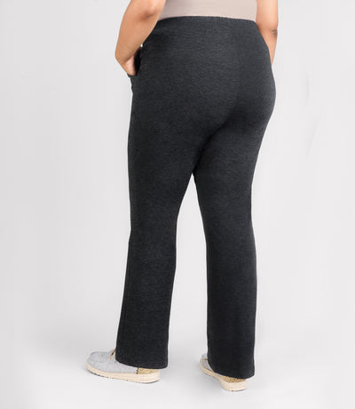 JunoActive model, facing back, wearing SoftSupreme pocketed lounge pant in color heather black. Her left hand is in her left pocket and right arm dropping by left side.
