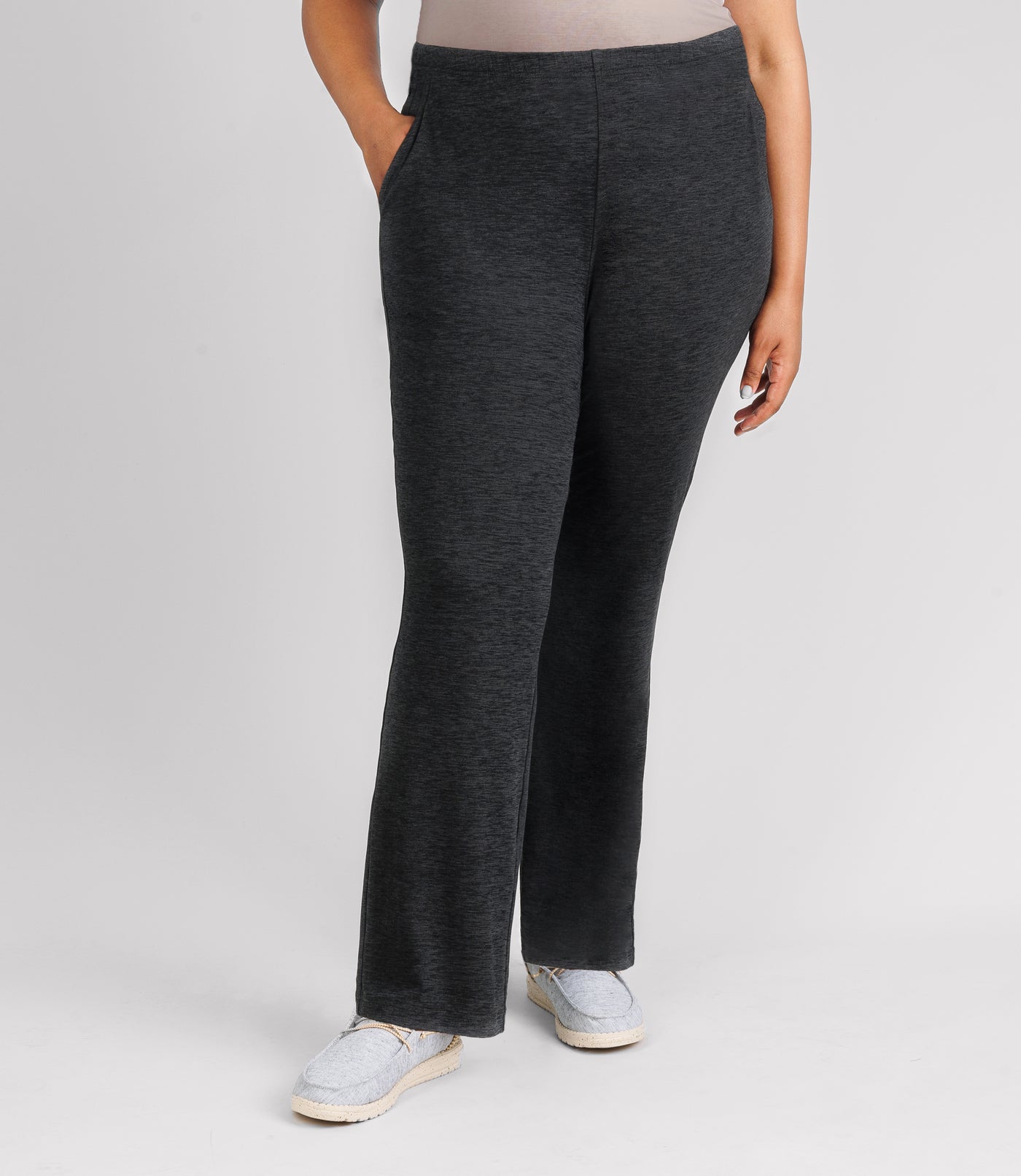 JunoActive model wearing SoftSupreme pocketed lounge pant in color heather black. Her right hand is in her right pocket and left arm dropping by left side.