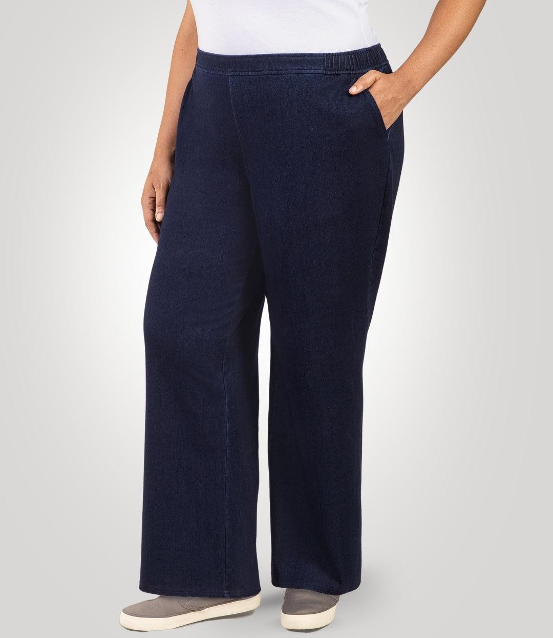 Plus size woman, facing front, wearing JunoActive's Wide Leg Stretch Twill Plus Size Pant. Her left hand is in her left pant pocket and right hand and arm is draping on her right side. Woman is standing on a beige colored backdrop.
