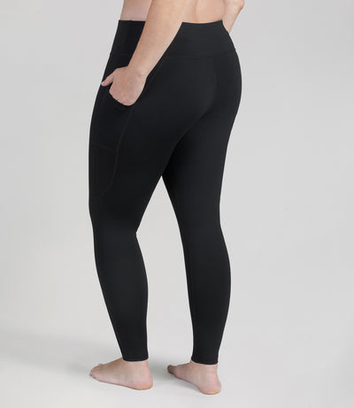 Bottom half of plus sized woman, back view, wearing JunoActive JunoStretch Side Pocket Legging in black. The pants are full length and have pockets on each side.