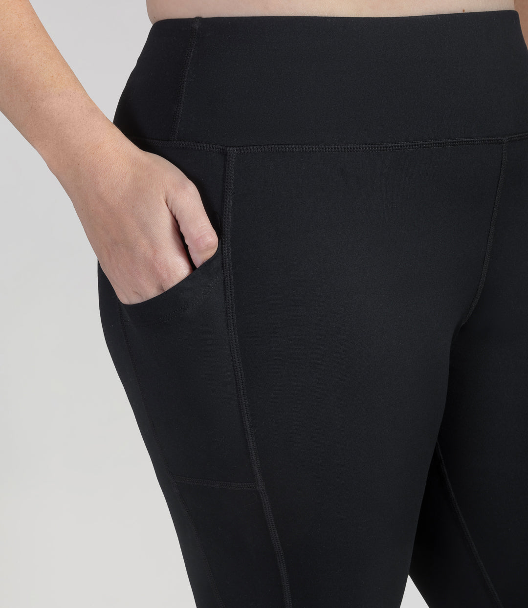 Close up of bottom half of plus sized woman, back view, wearing JunoActive JunoStretch Side Pocket Legging in black. The pants are full length and have pockets on each side.