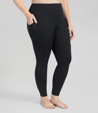 Bottom half of plus sized woman, facing front and angled to side, wearing JunoActive JunoStretch Side Pocket Legging in black. The pants are full length and have pockets on each side.