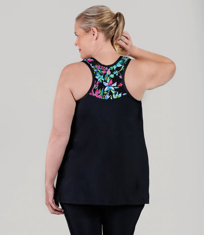 Plus size model wearing JunoActive's QuikEnergy Kona plus size tankini, featuring Night Lillies and black print, facing back with right hang up by head. 