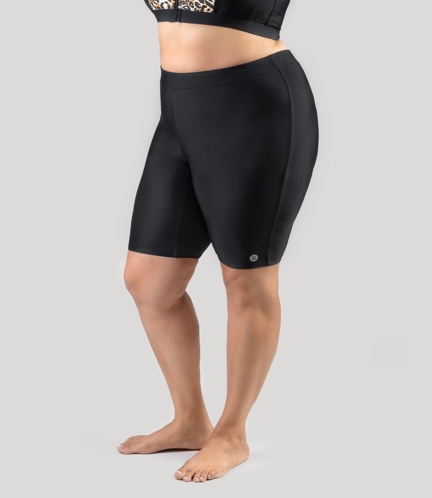 Plus size model, facing front, wearing QuikEnergy Swim plus size Bike Shorts and falls a couple inches above the knee.