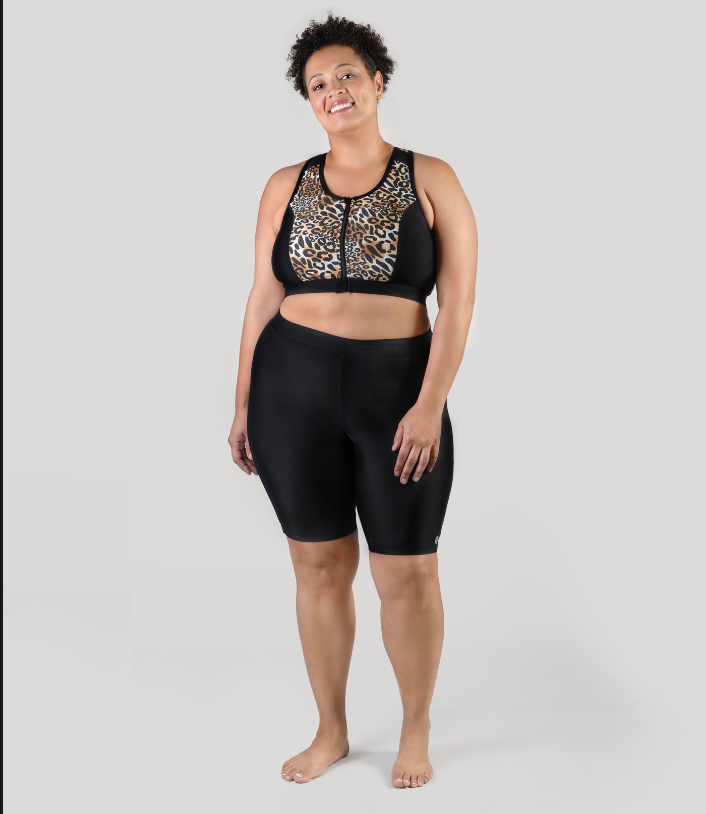 Plus size model, facing front, wearing QuikEnergy Swim plus size Bike Shorts and falls a couple inches above the knee. Model is wearing zip swim bra on top.