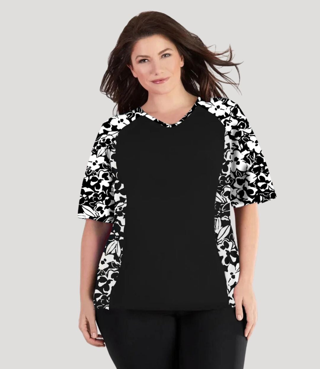 Plus size woman, facing front wearing JunoActive QuikEnergy Lite Swim and Beach short Sleeve Top Hibiscus Black. Solid Black on the center torso and Hibiscus print on the sleeves and side panels. The short sleeves end at the elbow.