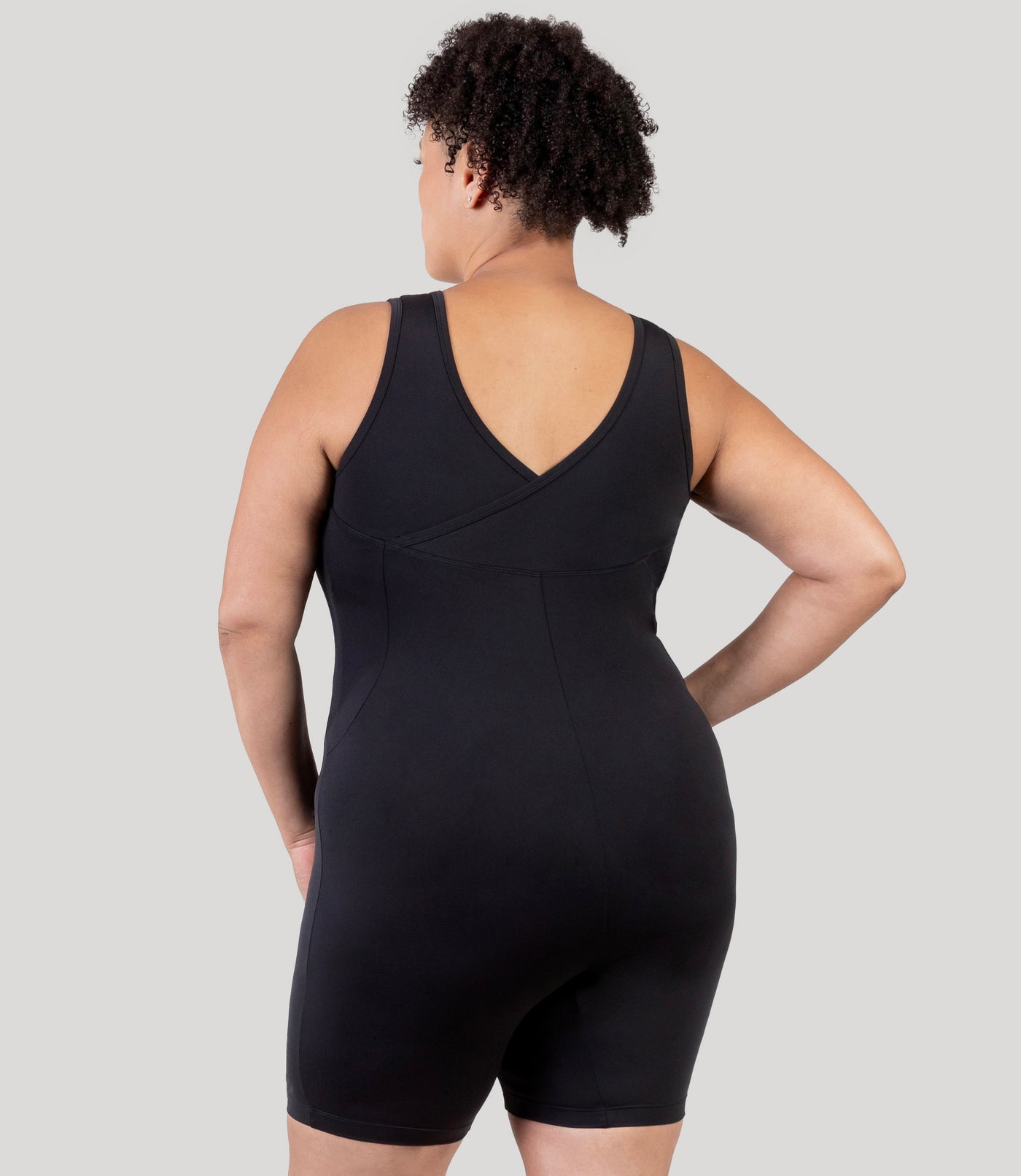 Plus size woman, facing back, wearing JunoActive's Aquasport Crossback Plus Size Aquatard in color black.