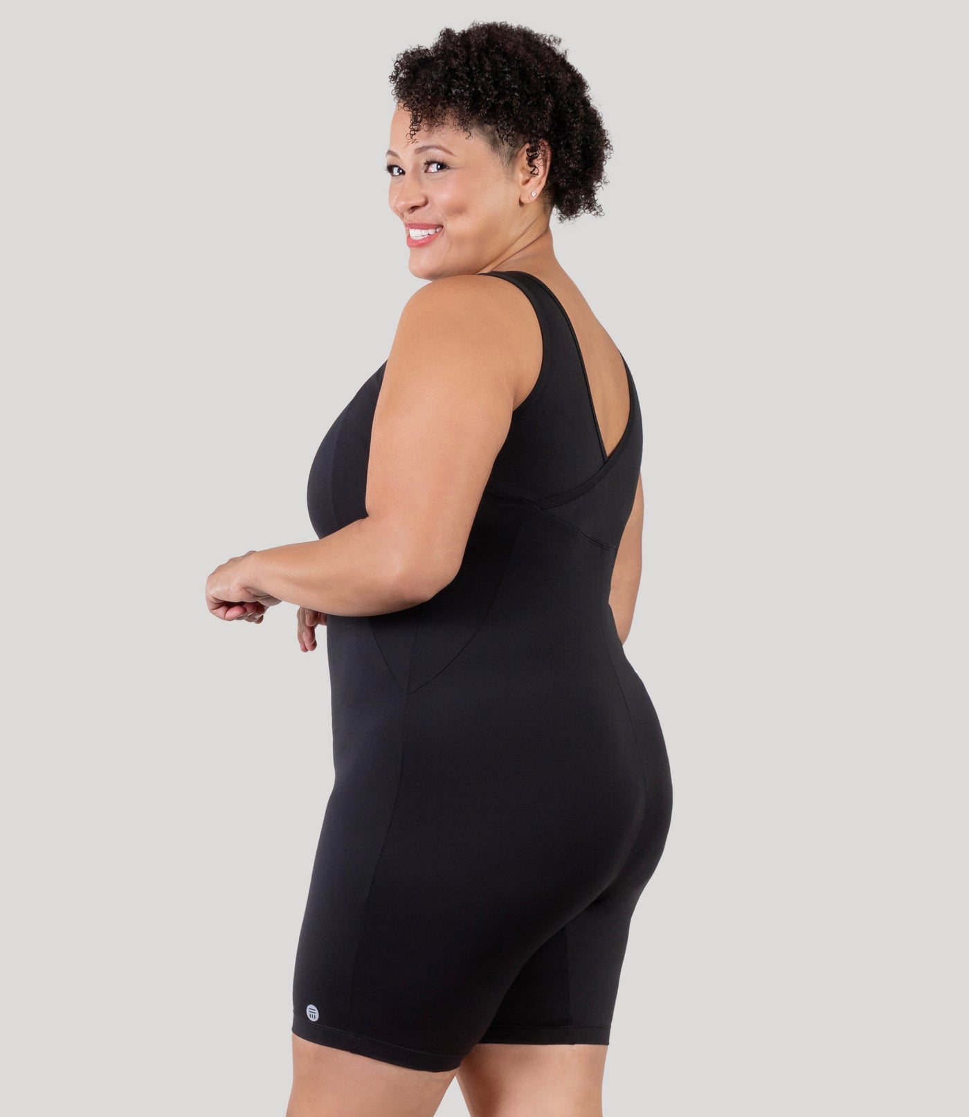 Plus size woman, facing side, wearing JunoActive's Aquasport Crossback Plus Size Aquatard in color black.