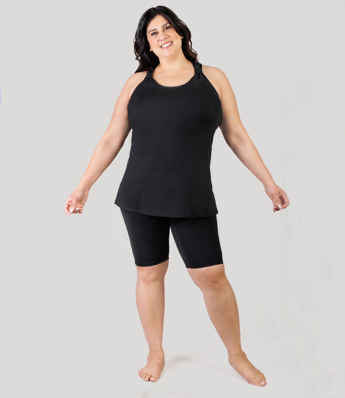 Plus size model, facing front full body, wearing JunoActive's AquaSport Hanalei Plus Size Tankini Top in color black.