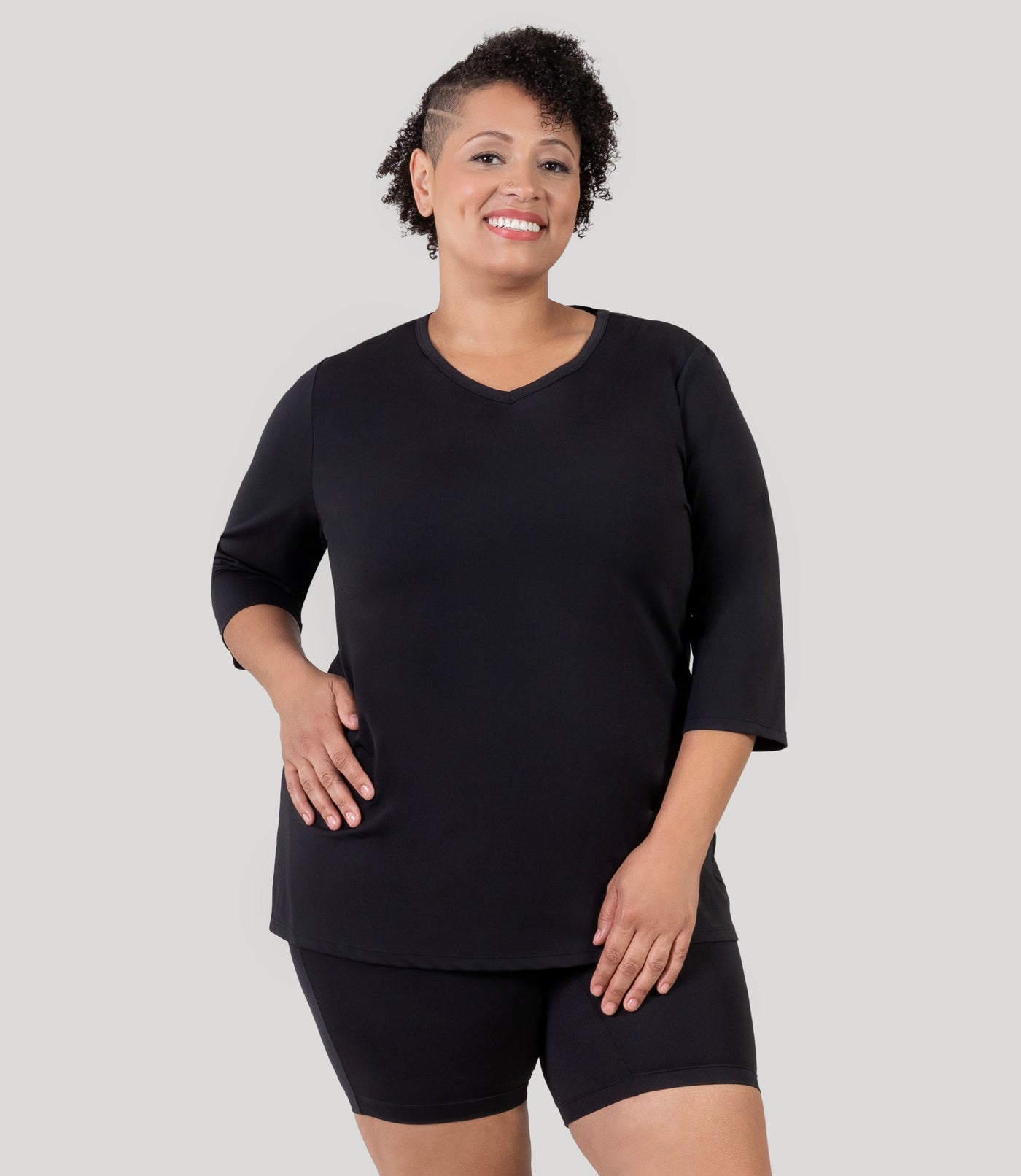 Plus size woman, facing front, wearing JunoActive's Aquasport 3/4 Sleeve Plus size Rash Guard in color black.