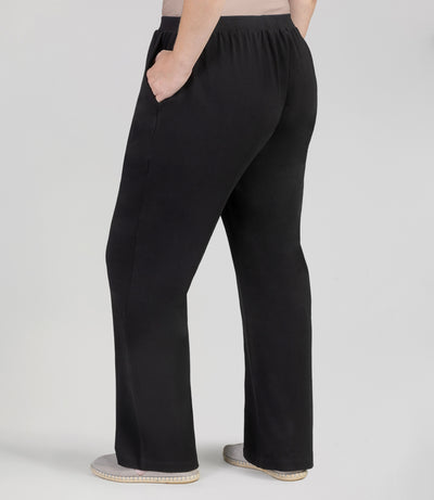 Back view, plus sized woman, wearing JunoActives UltraKnit Slash Pocket Pant, hands in pockets, hemline full length and in black.