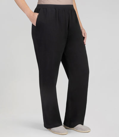 Front view, plus sized woman, wearing JunoActives UltraKnit Slash Pocket Pant, hands in pockets, hemline full length and in black.