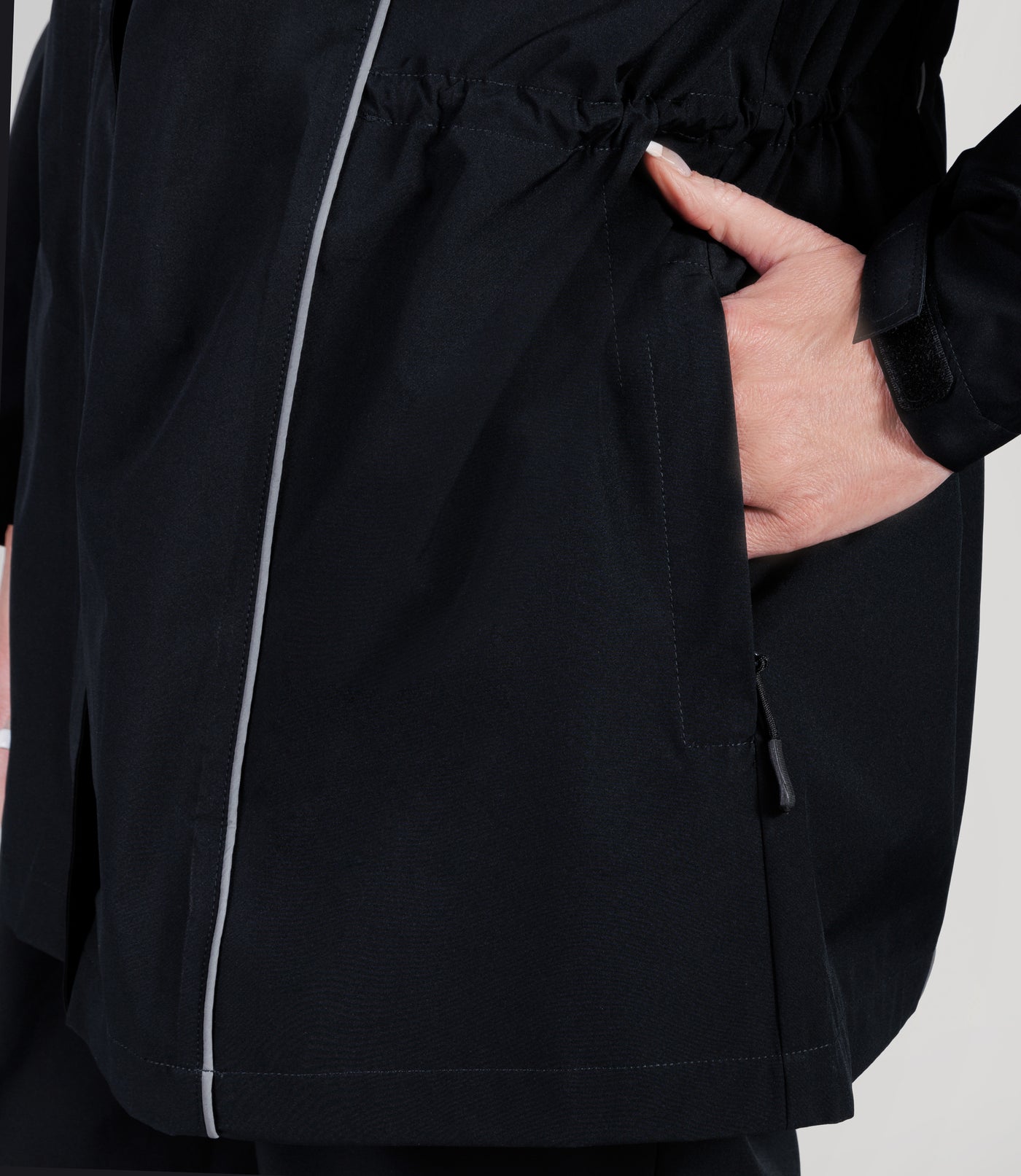 Close up of plus size model, wearing JunoActive's Adventure Wind and Rain Jacket in color black. Zoomed in to the pocket with her hand half in.