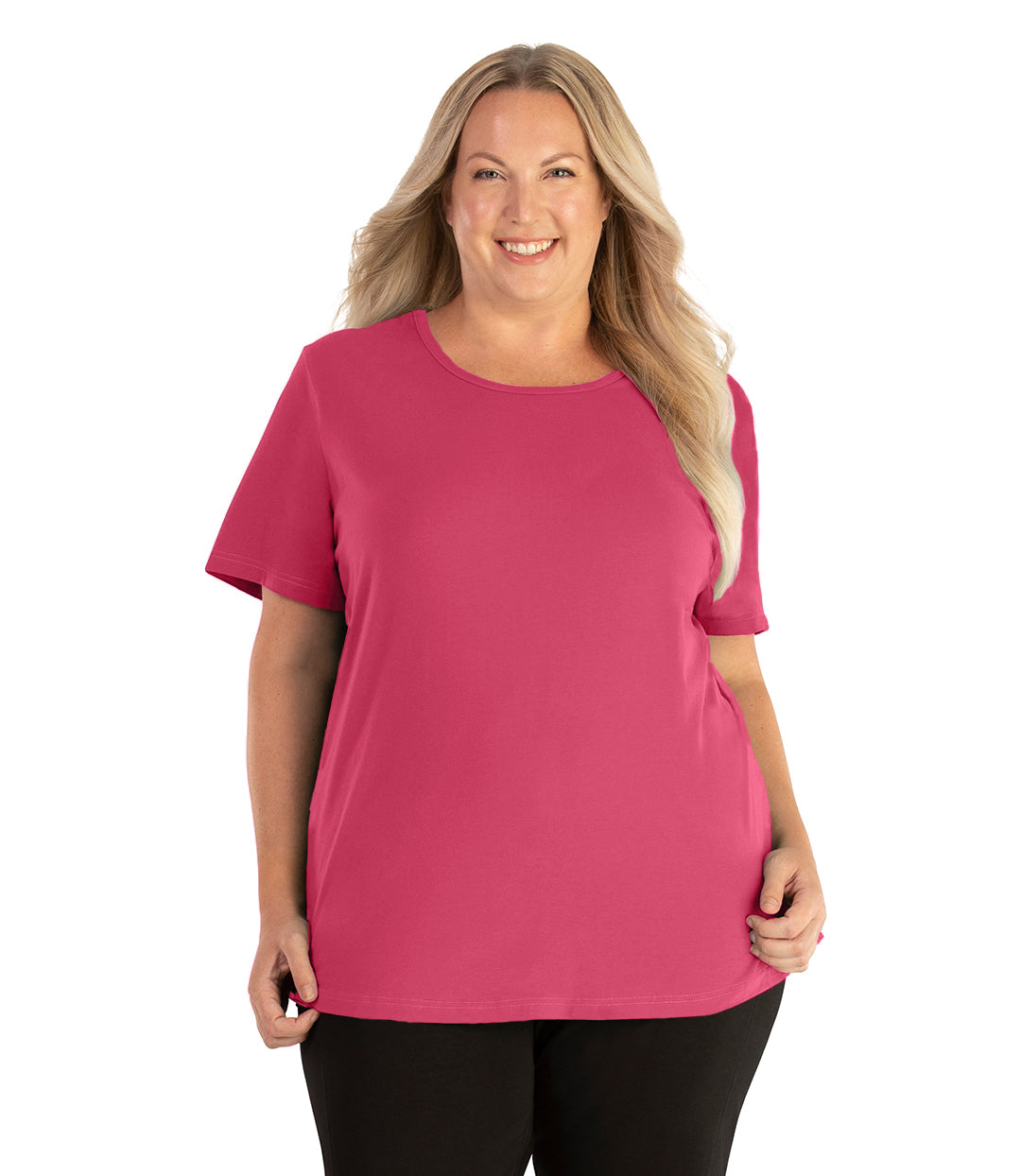 Plus size woman, facing front, wearing JunoActive plus size Stretch Naturals Lite Short Sleeve Scoop Neck Top in the color carnation pink. She is wearing JunoActive Plus Size Leggings in the color black.