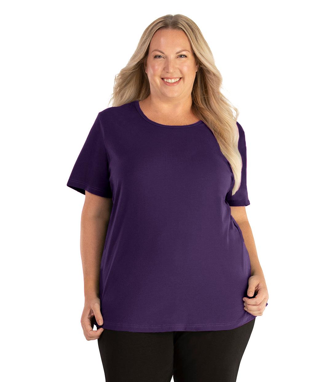 Plus size woman, facing front, wearing JunoActive plus size Stretch Naturals Lite Short Sleeve Scoop Neck Top in the color deep plum. She is wearing JunoActive Plus Size Leggings in the color black.