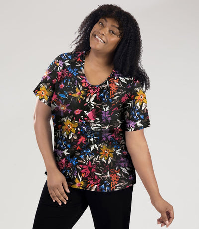 Model, facing front, wearing Junonia Lifestyle Printed Short Sleeve V-Neck top in floral forest print.