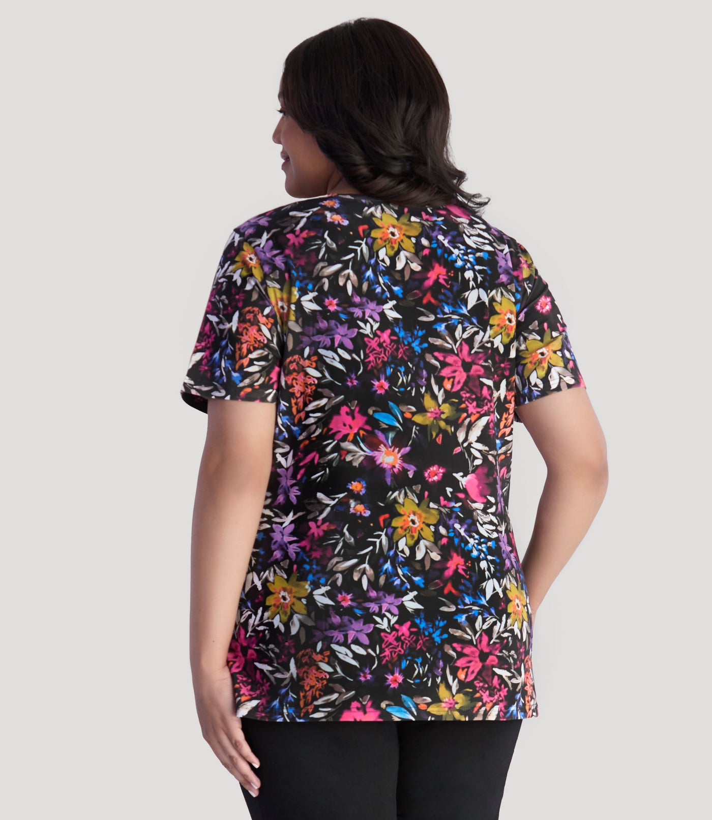 Model, facing back, wearing Junonia Lifestyle Printed Short Sleeve V-Neck top in floral forest print.