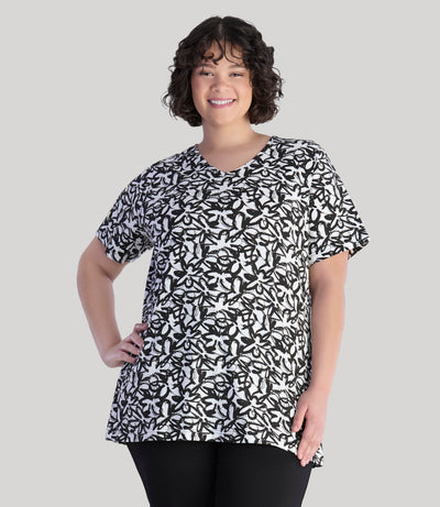 Model, facing front, wearing JunoActive's Junonia Lifestyle printed short sleeve neck top in color black and white wildflower print.
