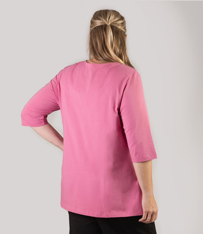 Plus size woman, facing back, wearing JunoActive’s Stretch Naturals Lite 3/4 Sleeve V-neck Tunic, color mulberry. left arm hand on hip and right arm by side, chicken with a crown graphic.