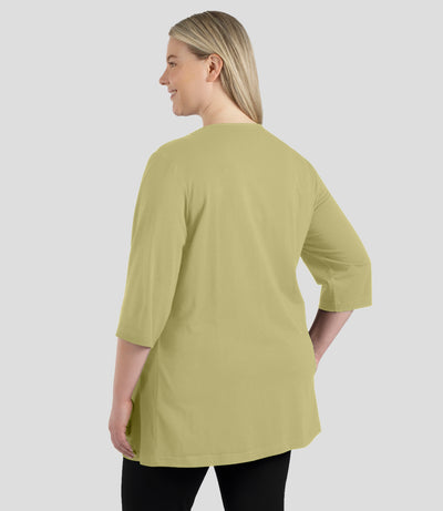 Back of Model wearing JunoActive's designer graphic 3/4 sleeve v-neck tunic in color aloe green.