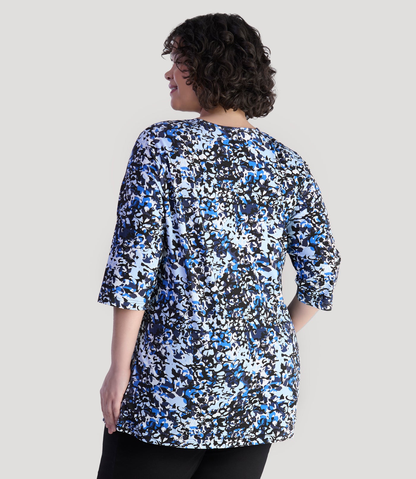 Model, facing back, wearing JunoActive's Junonia Lifestyle Printed three quarter sleeve pocketed top in color blue melange print.