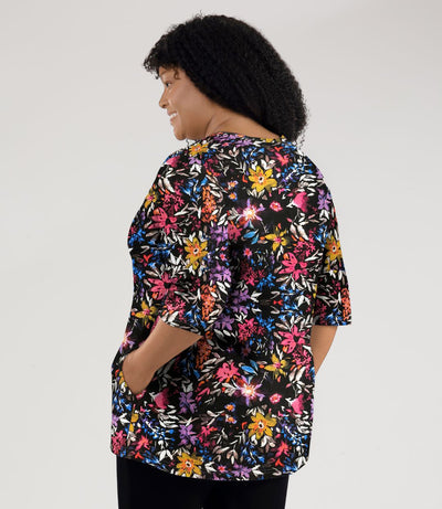 Model, facing back, wearing JunoActive's Junonia Lifestyle Printed three quarter sleeve pocketed top in floral forest print.