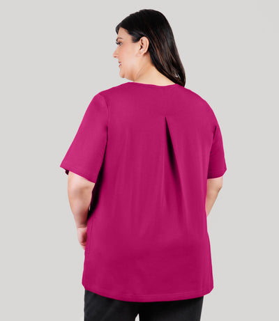 Plus size model, facing back and looking to the side at profile, wearing JunoActive's Stretch Naturals Lite Elbow Length V-Neck plus size Top in color magenta.