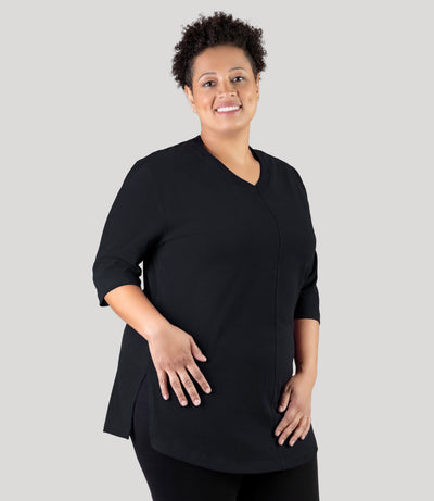 Plus size woman, facing front, wearing JunoActive plus size Legacy Cotton Casual Tunic in the color Black. She is wearing JunoActive Plus Size Leggings in the color black. 