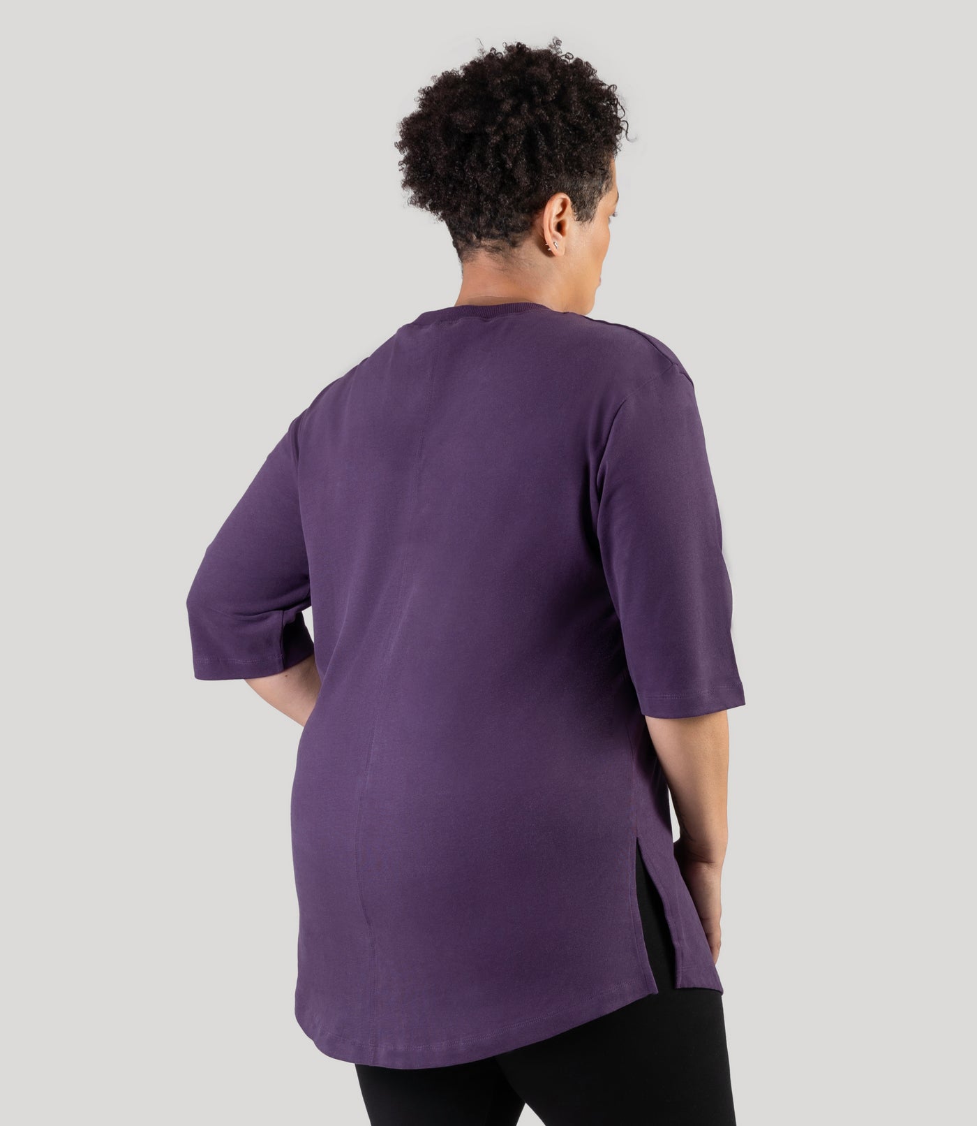 Plus size model, facing back with side slit showing, wearing JunoActive's Legacy Cotton Casual plus size tunic top in color deep berry.