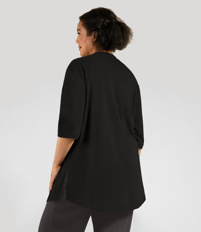 Plus size woman, facing back, wearing JunoActive's Legacy Cotton Plus Size Casual Tunic in color black.