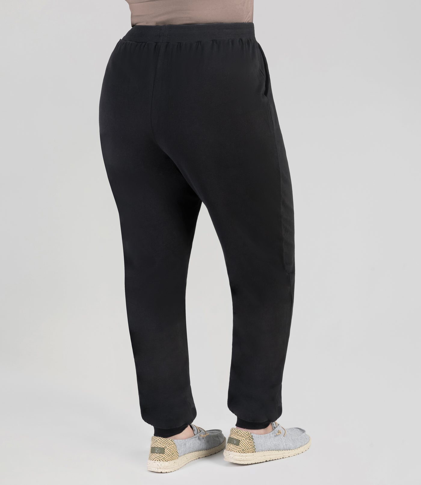 JunoActive model facing back, wearing Legacy Cotton Casual Pocketed pant in color black. Pants fall at ankles with loose cuff.