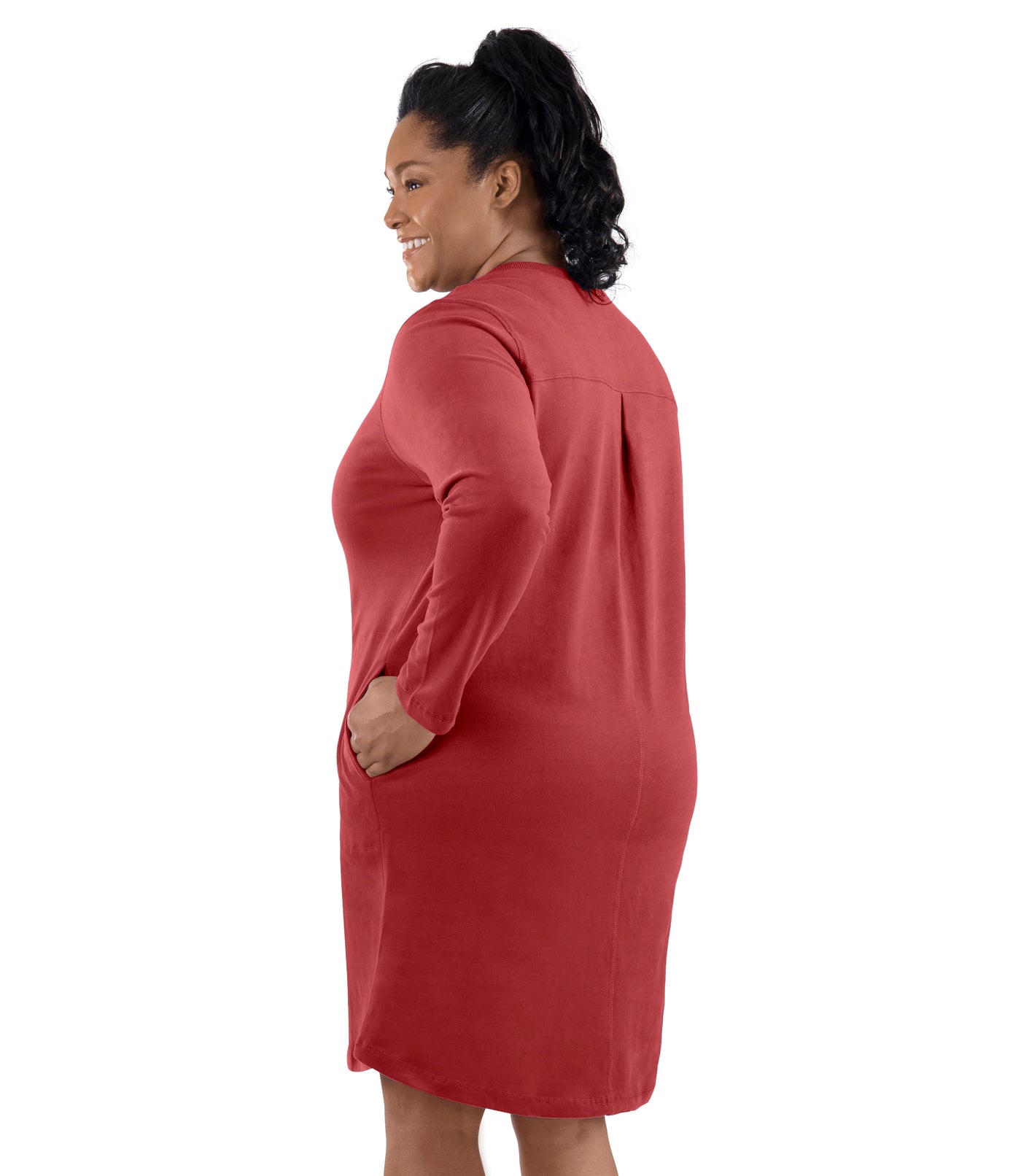 Plus-size model, facing back, left hand in dress pocket. Wearing JunoActive's Legacy Cotton Casual Pocketed Long Sleeve Dress in Sedona Red.