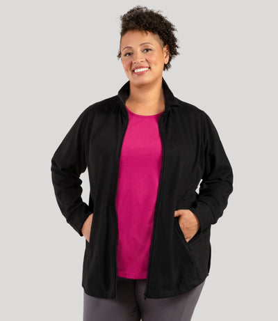 Plus size woman, facing front with hands in both pockets of jacket, wearing JunoActive's Legacy Cotton Casual Mock Neck Zip up plus size jacket in color black. Jacket is unzipped.