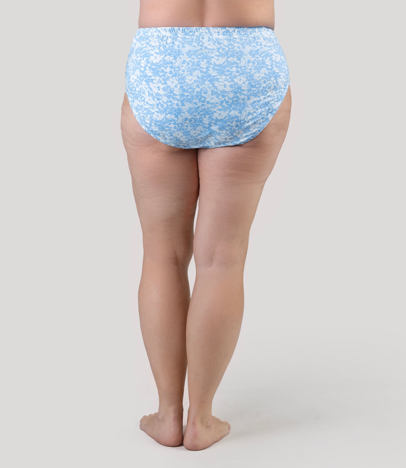 Lower half of plus size model, facing back, wearing JunoActive's Classic Brief in color blue blossoms print.