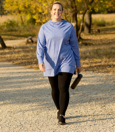 Plus size model, wearing JunoActive's Softwik Long Sleeve Hoodie Shirt. Woman is walking in forest on gravel path.