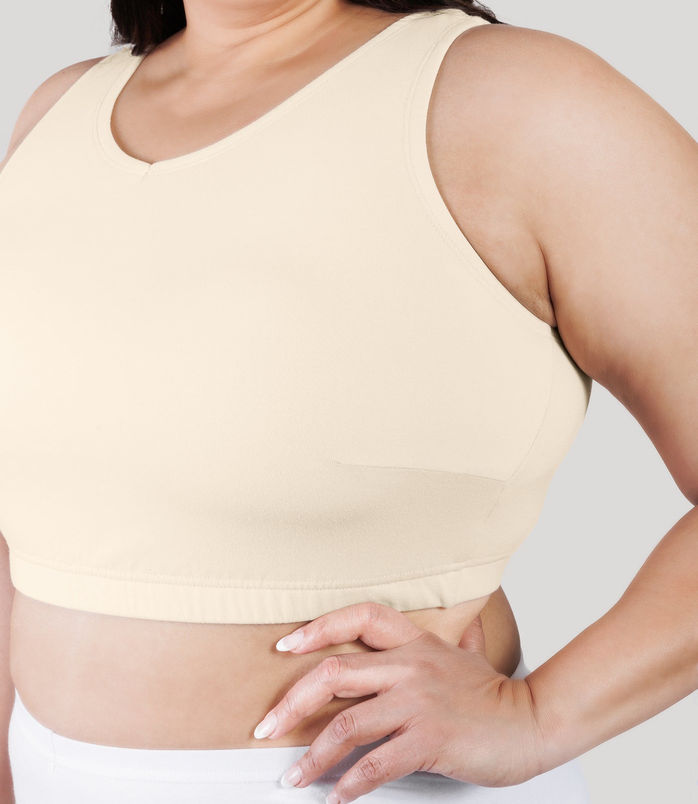 Close up of plus size model, facing front, wearing stretch naturals full fit V-neck plus size bra in color sandy.