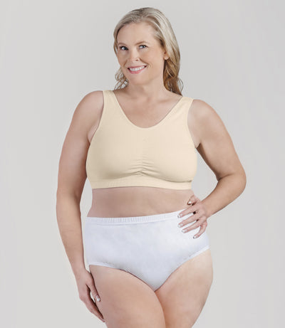 Plus size woman, facing front, wearing JunoActive Stretch Naturals Shirred Bra Top. Bra is gathered in middle and is a scoop top neck. Straps are wide and bra color is sandy.