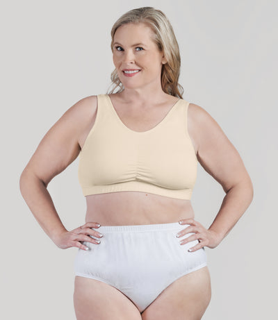 Plus size woman, facing front, wearing JunoActive Stretch Naturals Shirred Bra Top. Bra is gathered in middle and is a scoop top neck. Straps are wide and bra color is sandy.