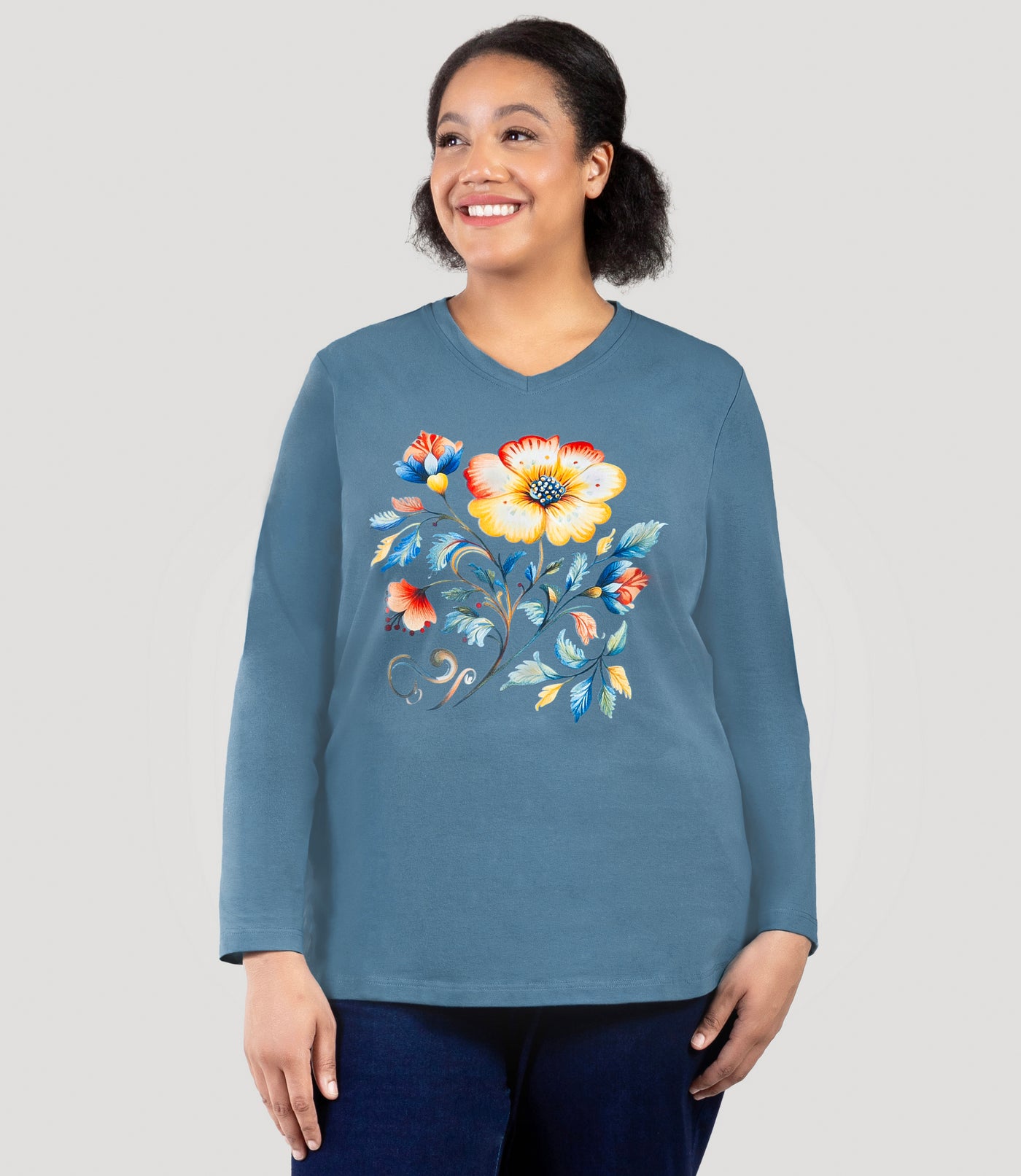 Plus size woman, facing front, wearing JunoActive's Designer Graphic Long Sleeve V-neck Plus Size Top in Flora Flower Graphic in teal blue.