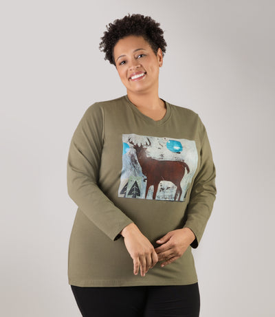 Plus size woman, facing back looking left, wearing JunoActive plus size Stretch Naturals Long Sleeve V-Neck Top in the color Moss Green with a moose graphic. She is wearing JunoActive Plus Size Leggings in the color Black.