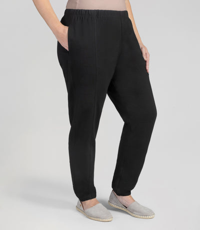 Bottom half of plus sized woman, front view, wearing junoactives stretch naturals jogger pockets black. The pants are full length and have pockets on each side.