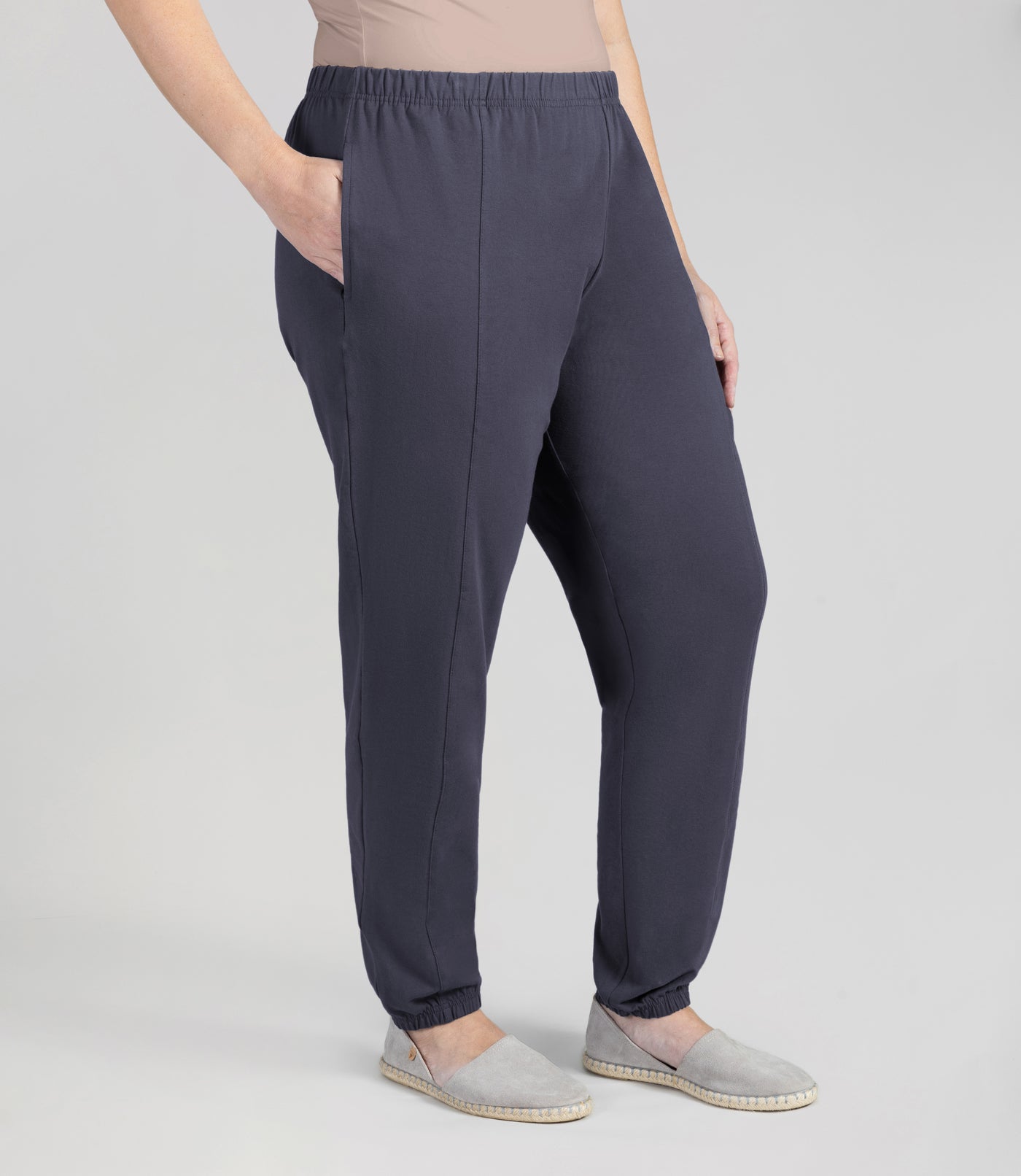 Bottom half of plus sized woman, front view, wearing junoactives stretch naturals jogger pockets oak gray. The pants are full length and have pockets on each side.