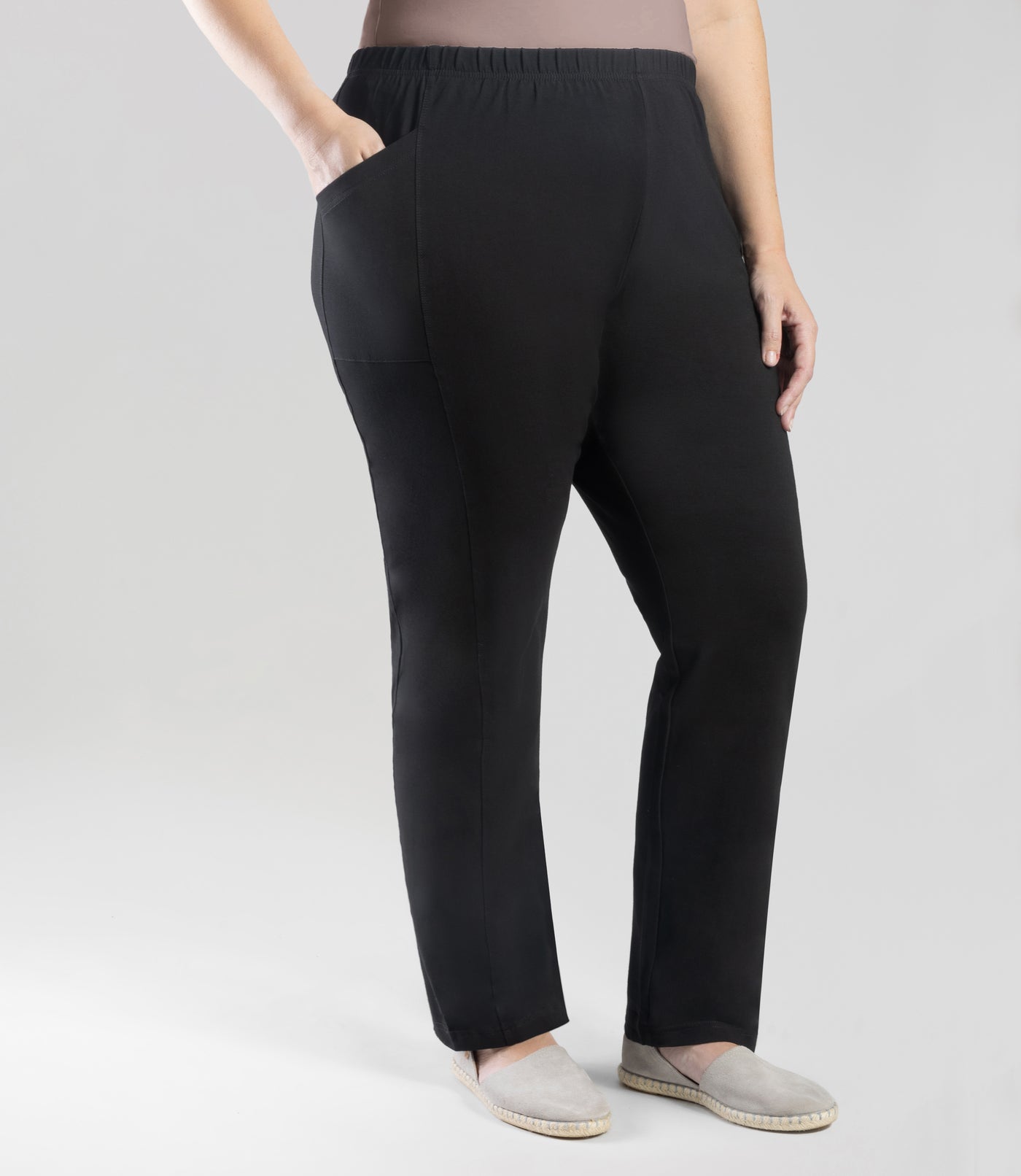 Bottom half of plus sized woman, front view, wearing JunoActive Tall Stretch Naturals Side Pocket Loose Fit Leggings in color black. Bottom hem is at the ankle. Woman is wearing black sneakers.
