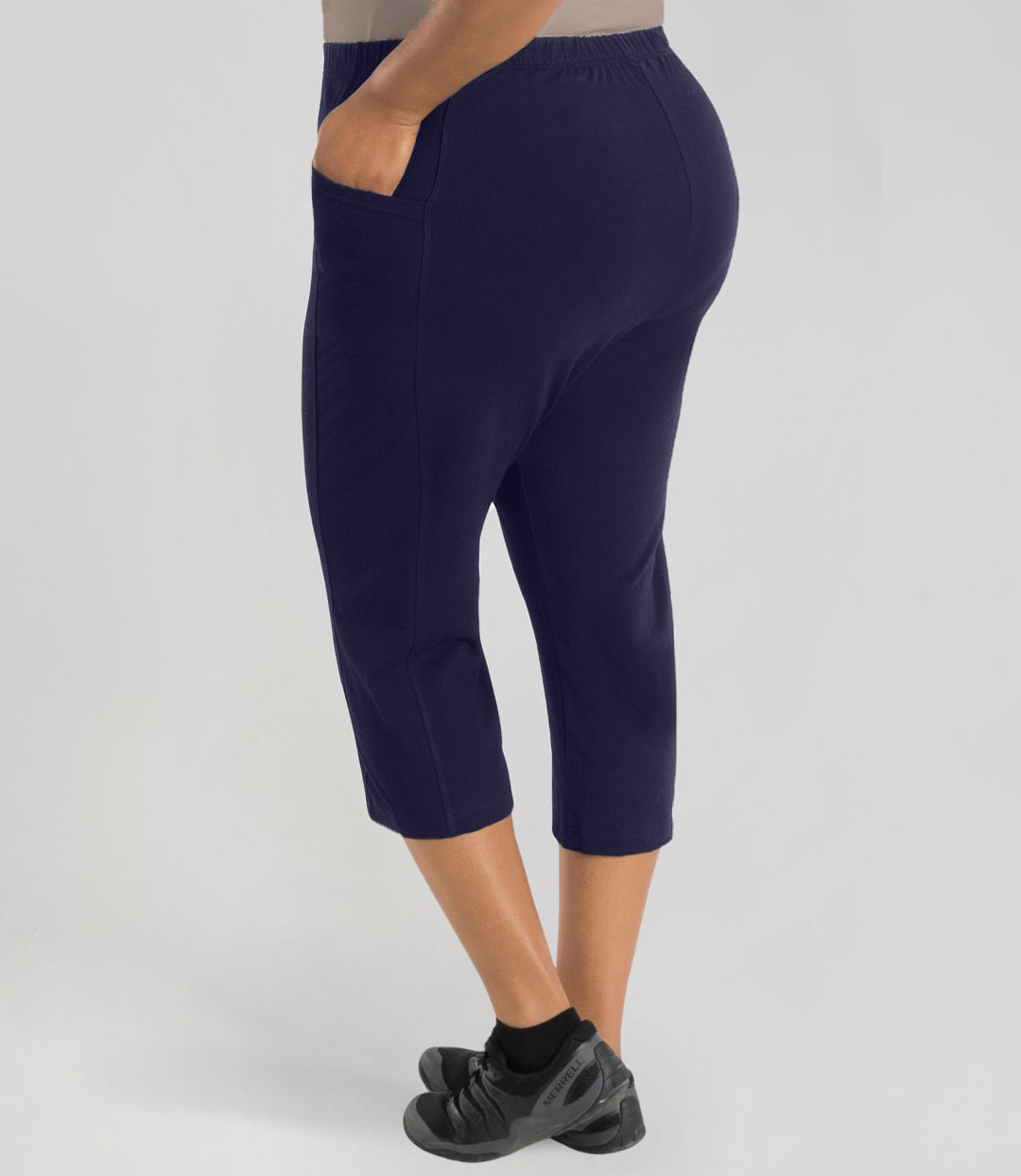 Plus size model, facing back, wearing Stretch Naturals Side Pocket Capri Classic Colors in color dark navy.