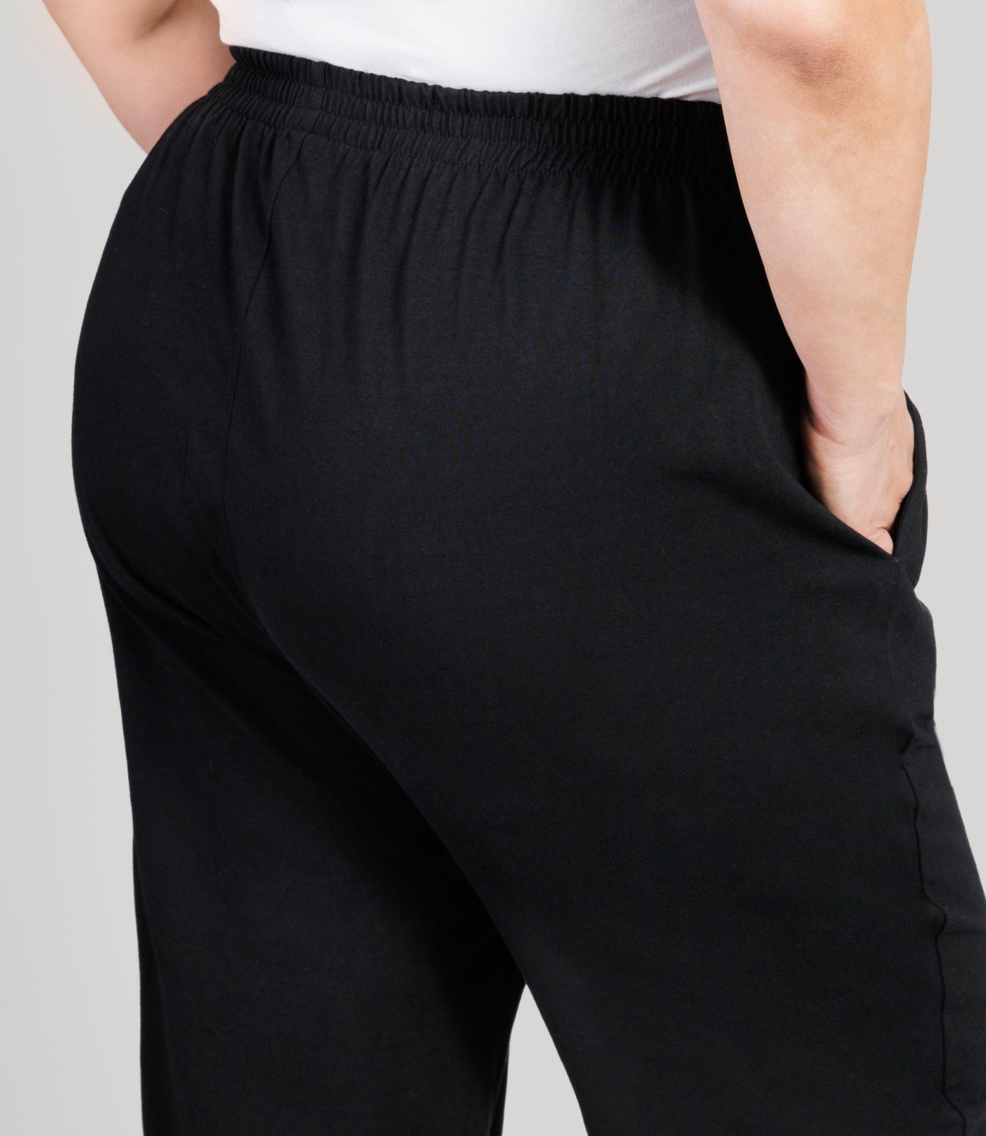 Plus size model, facing back close up, lower half of body from waist down, wearing JunoActive's Stretch Naturals Full Fit Pear plus size Pant in color black.