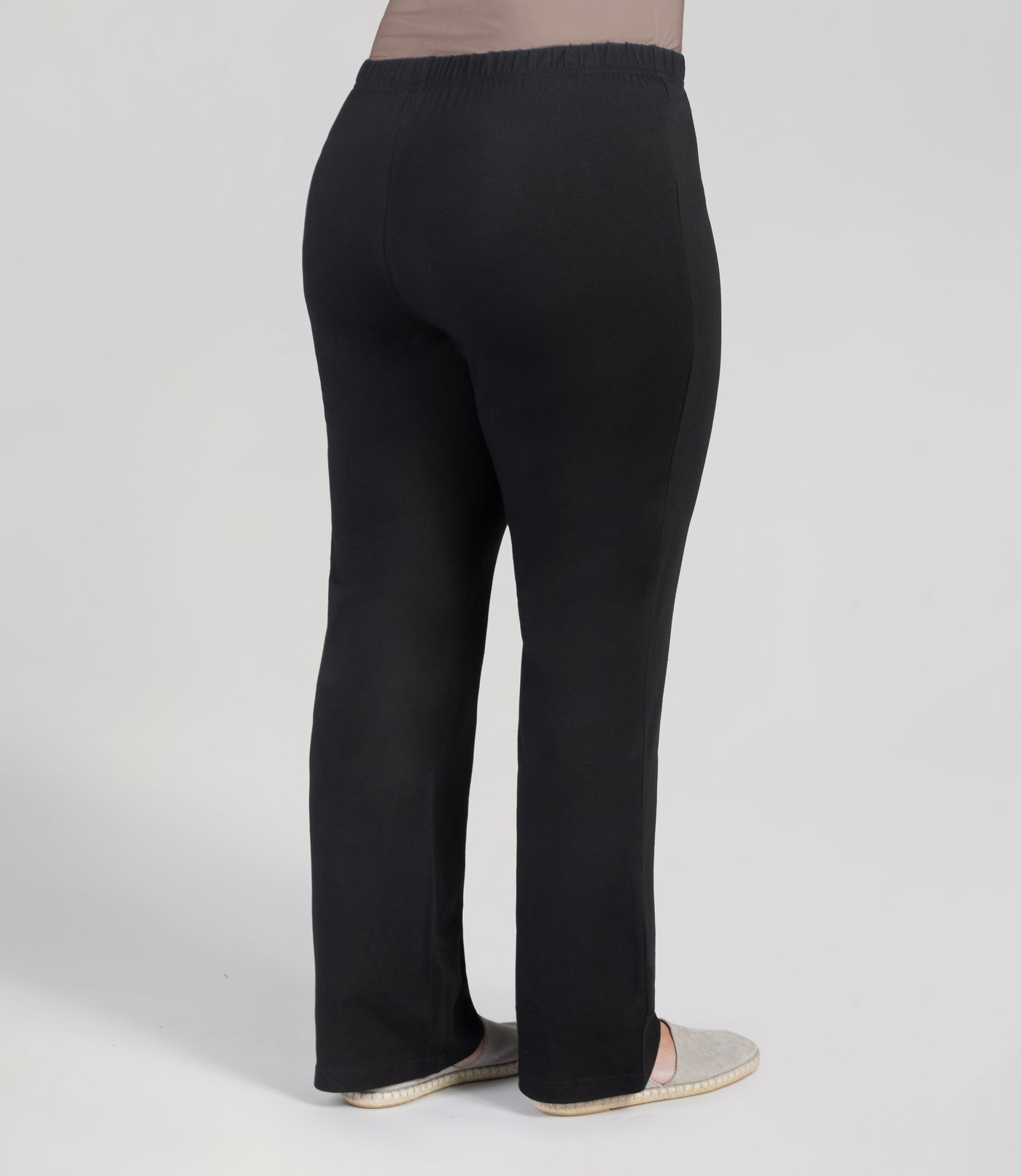 Back view, bottom half of plus sized woman, wearing JunoActives Stretch Naturals loosest bootcut leggings and are full length with an elastic waist band in black.