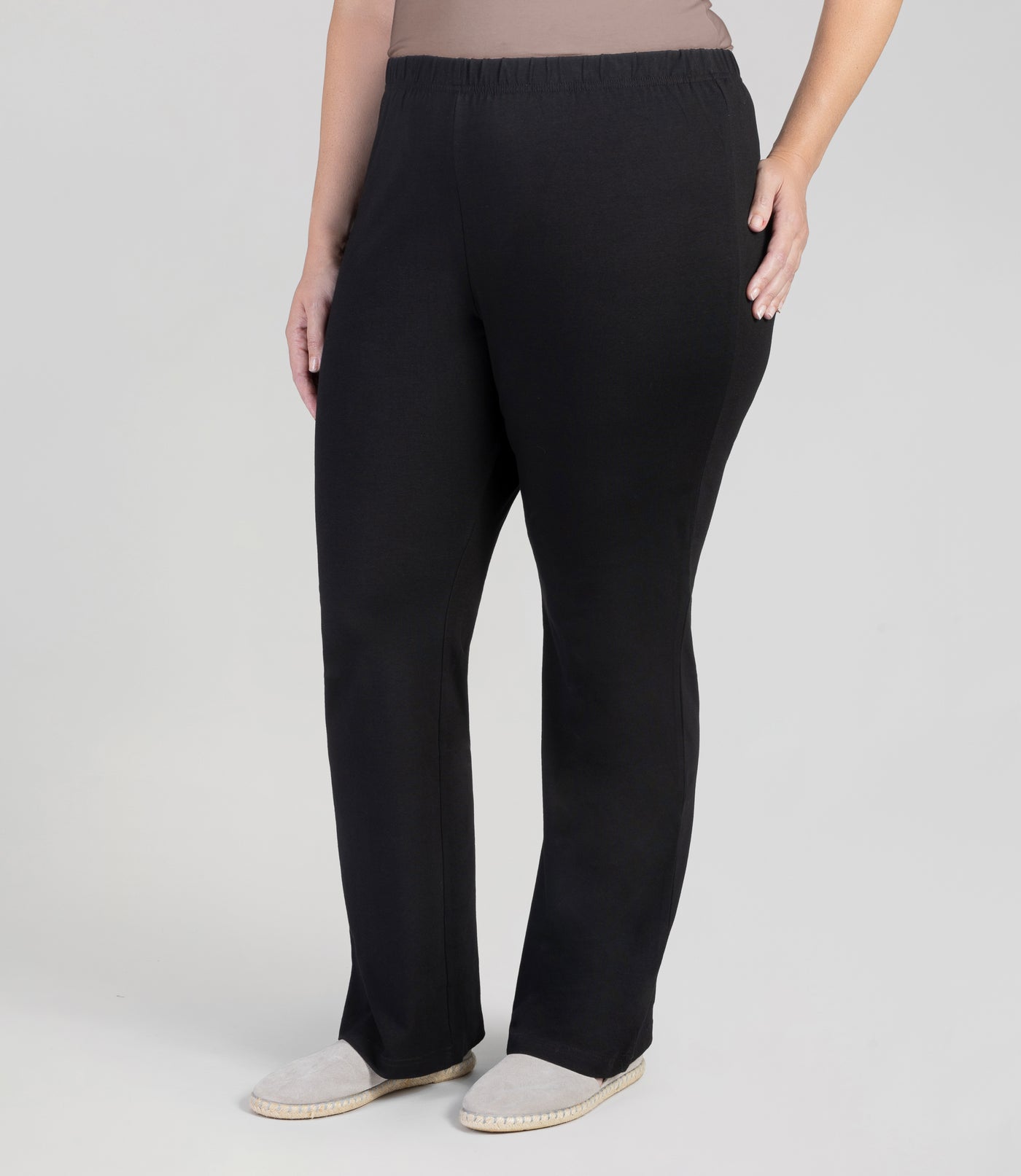 Front view, bottom half of plus sized woman, wearing JunoActives Stretch Naturals loosest bootcut leggings and are full length with an elastic waist band in black.