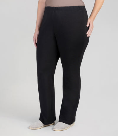 Plus size model, facing front, wearing Stretch Naturals Loose Fit Boot Cut Leggings in color black.