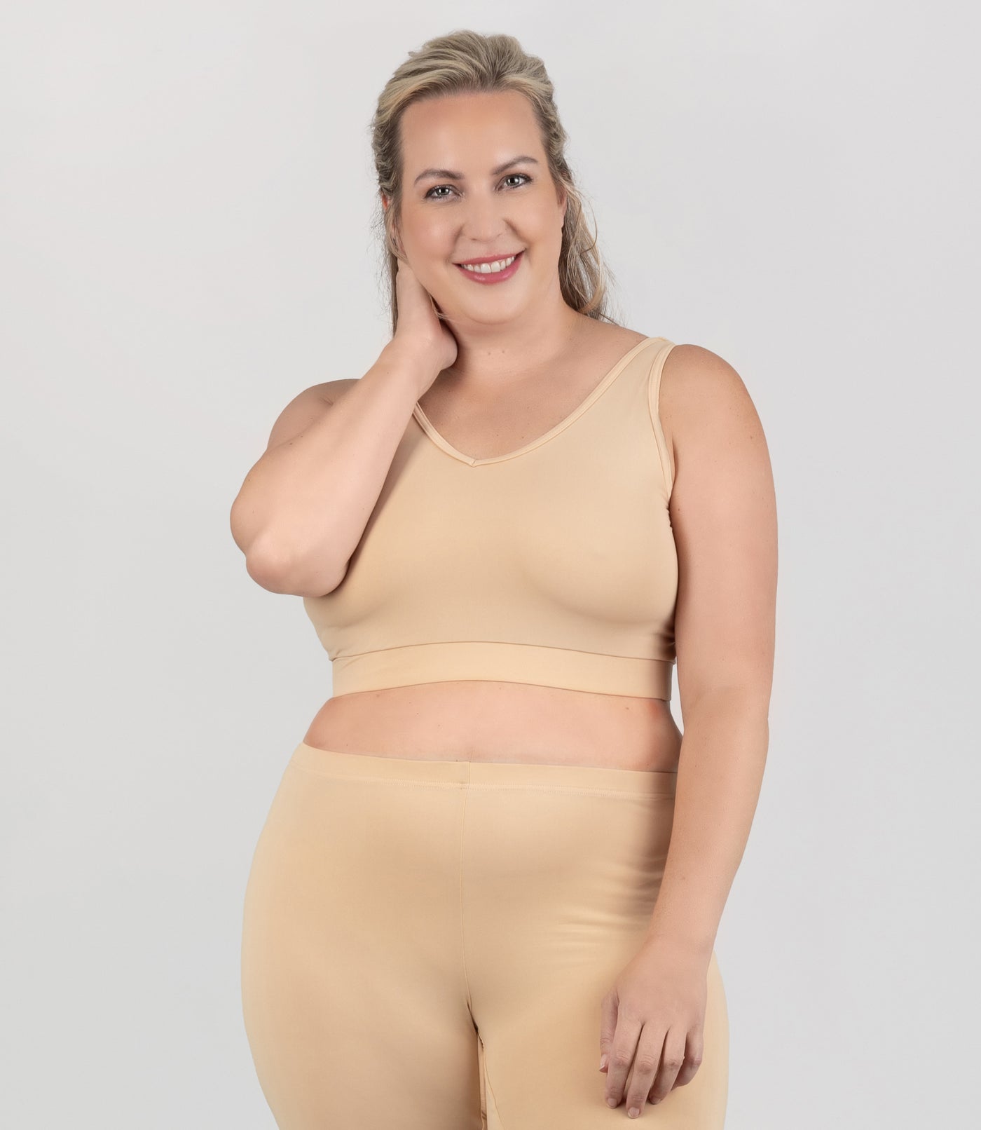 Plus size woman, facing front, wearing JunoActive plus size Junowear Hush V-Neck Bra in Ecru. The woman is wearing an ecru Junowear Hush Boxer brief. 